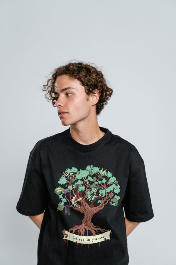 a young man wearing a black t-shirt with the I believe in fairies design by Natalia Salvador